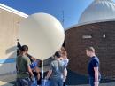 High School Students from last year’s High Altitude Balloon Camp, look over their ballon before launch. [Photo courtesy of Drew Deskur, KA1M]